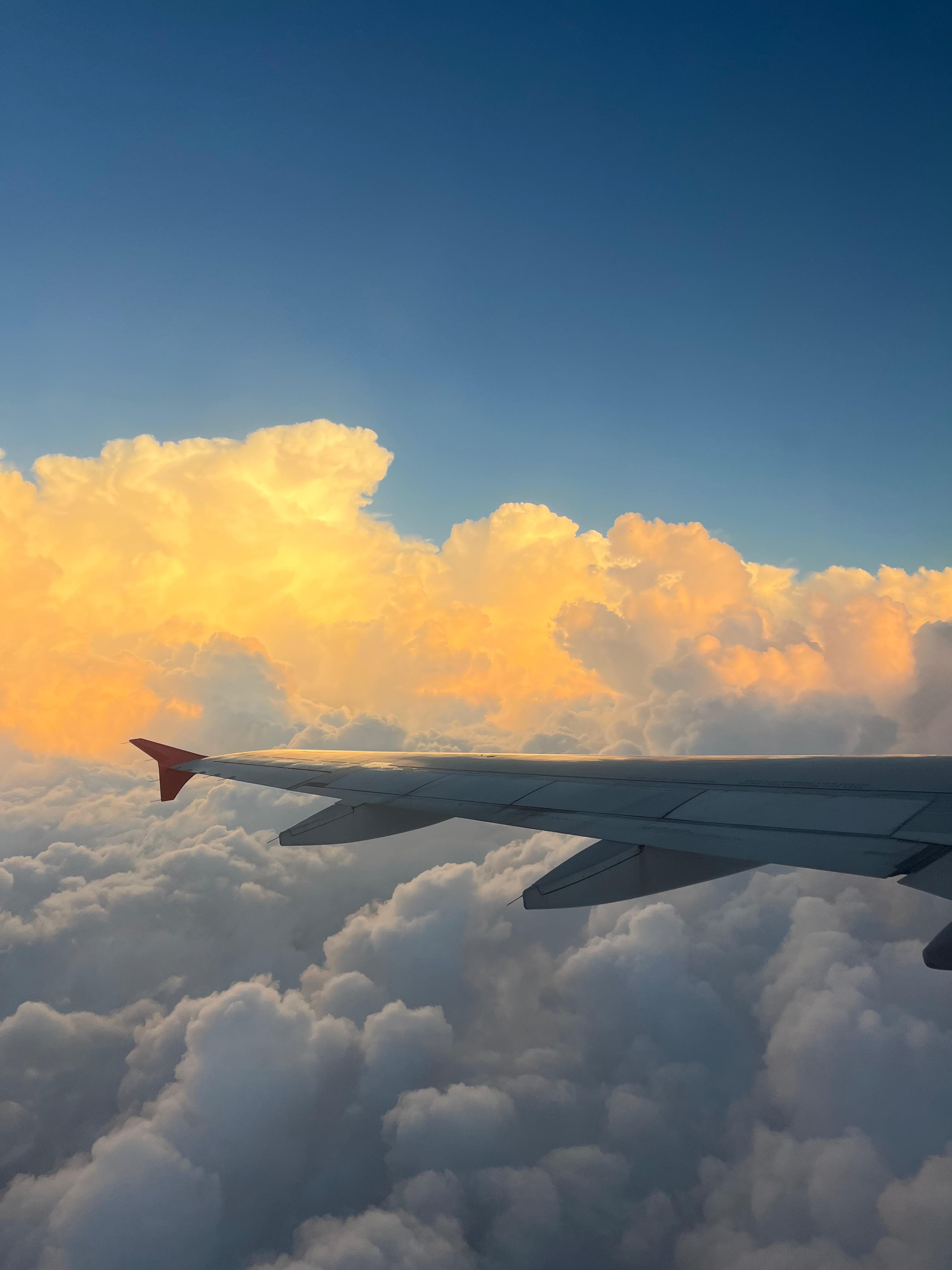 Pôr do sol visto pela janela do avião, com nuvens douradas acima da asa